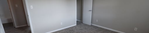 A room with carpeted floor and two doors.