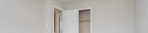 A white room with a carpeted floor and a doorway leading to another room.