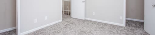 Empty room with white walls and carpeted floor.