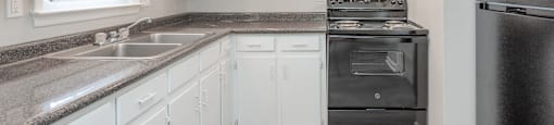 A kitchen with white cabinets and a black refrigerator.