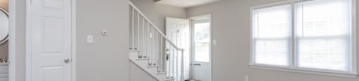 A spacious room with a staircase leading to the second floor.