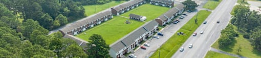 an aerial view of a building next to a field and a highway