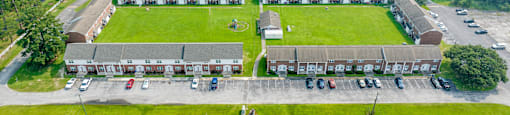 an aerial view of a building with a field and a parking lot
