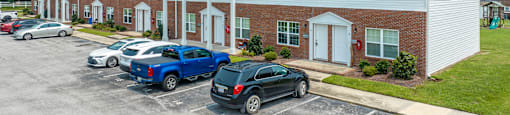 a parking lot in front of a white building with cars parked in front