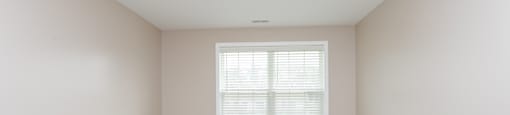 A room with a carpeted floor and a window with blinds.