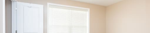 A room with a white door and a window with blinds.