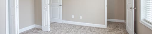 A room with a carpeted floor and two open doors.