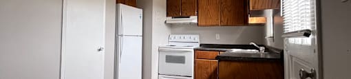 A kitchen with white appliances and wooden cabinets.