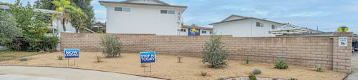 a retaining wall with signs in front of some houses