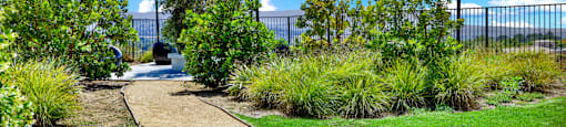 a walkway through a park with trees and grass at Monterra Ridge Apartments, Canyon Country, California