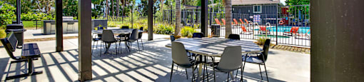 a patio with tables and chairs under awning at Monterra Ridge Apartments,California