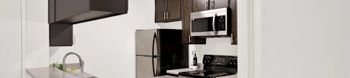 a kitchen with stainless steel appliances and dark cabinets at Monterra Ridge Apartments, California