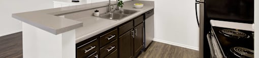 a kitchen with dark wood cabinets and white counter top and a black refrigerator at Monterra Ridge Apartments, Canyon Country ,91351