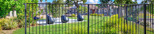 a playground in a park behind a metal fence at Monterra Ridge Apartments, Canyon Country ,91351