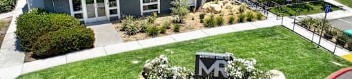 the front of a building with a lawn and a sign in front of it at Monterra Ridge Apartments, Canyon Country, California