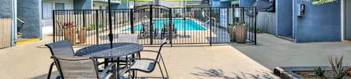 our patio has tables chairs and umbrellas and a pool at Sunset Square Apartments, West Covina, California, 91790