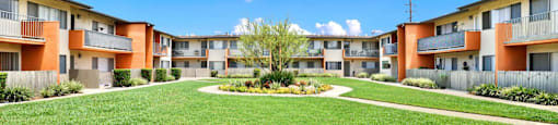 an exterior view of an apartment building with a grassy courtyard at Sunset Square Apartments, West Covina, California, 91790