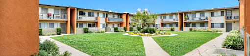 an exterior view of a courtyard at an apartment building with green grass at Sunset Square Apartments, West Covina, California, 91790