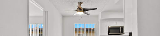 an empty kitchen with a ceiling fan and a window at Sunset Square Apartments, West Covina, California, 91790