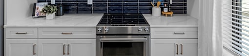 a kitchen with white cabinets and a stove and blue tiles at The Collection Charlotte in Charlotte, NC, 28205