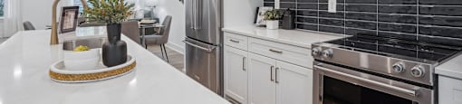 a white kitchen with stainless steel appliances and white counter tops at The Collection Charlotte in Charlotte, NC, 28205