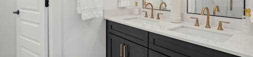 a white bathroom with black cabinets and a sink and a mirror at The Collection Charlotte in Charlotte, NC, 28205