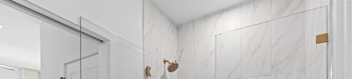 the master bathroom has a large shower with marble tile and a glass door at The Collection Charlotte in Charlotte, NC, 28205