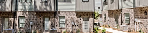 an apartment building with white siding and a brick facade at The Collection Charlotte in Charlotte, NC, 28205