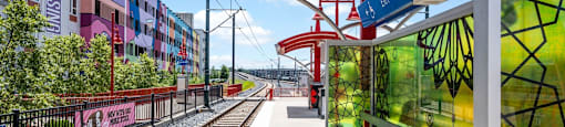 a train station with train tracks and buildings on the side of it at The Collection Charlotte in Charlotte, NC, 28205