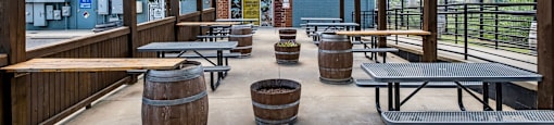 a covered patio with tables and barrels at The Collection Charlotte in Charlotte, NC, 28205