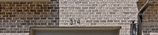 the side of a brick building with a gray garage door at The Collection Charlotte in Charlotte, NC, 28205