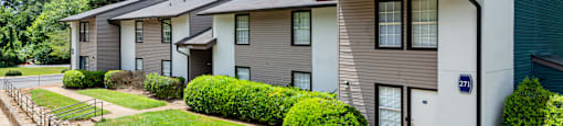 a white and gray apartment building with green grass and trees at Glen Hollow, Decatur, GA