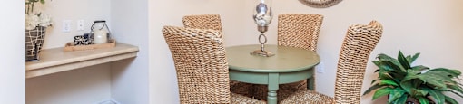 a dining room with wicker chairs and a green table
