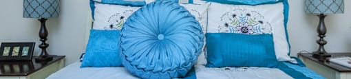 the master bedroom has a large bed with blue pillows and art on the wall