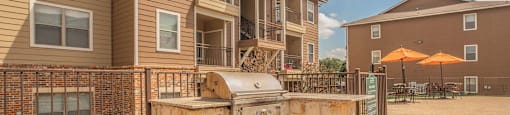 A sunny day at a residential complex with a fenced area and a stone structure at The Villages at Lost Creek Apartments, San Antonio, TX