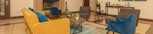 A living room with a yellow couch and a fireplace at The Villages at Lost Creek Apartments, San Antonio, TX