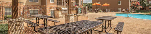 A patio with tables and benches under a wooden pergola at The Villages at Lost Creek Apartments, Texas