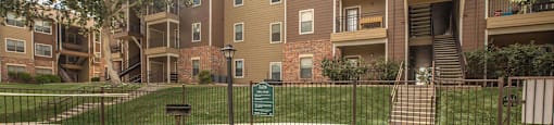 A picnic table and two benches are in front of a fence and apartment building at The Villages at Lost Creek Apartments, San Antonio, 78247