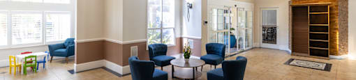 a large clubhouse with blue chairs and a table and a chandelier at Saratoga Resort Villa Apartments, Kissimmee, FL,  34746