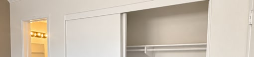A white closet with a door open and a small closet with lights inside.