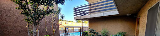 a path leading to a building with a pool and plants at Villa La Paz Apartments, California, 90706