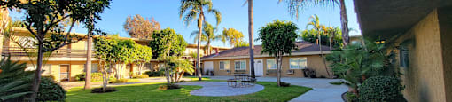 a courtyard with a picnic table and palm trees at Villa La Paz Apartments, California, 90706