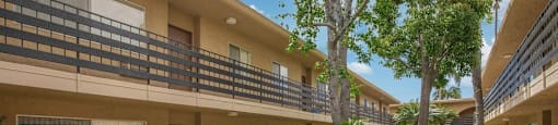 an apartment building with a courtyard and trees at Villa La Paz Apartments, Bellflower, California