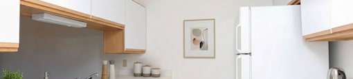 A kitchen with white cabinets and a white fridge.