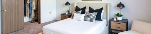 A bedroom with a large bed, a chair, and a wardrobe.