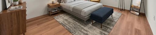 A bedroom with a large bed, a nightstand, a chair, and a rug.