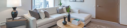 A living room with a white couch, a grey armchair, a wooden coffee table, and a grey rug.