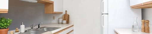 A white kitchen with a sink, stove, and refrigerator.