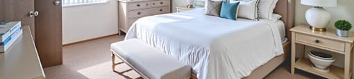 A bedroom with a large bed, a nightstand, and a dresser.