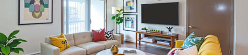 A living room with a yellow couch and a white coffee table.
